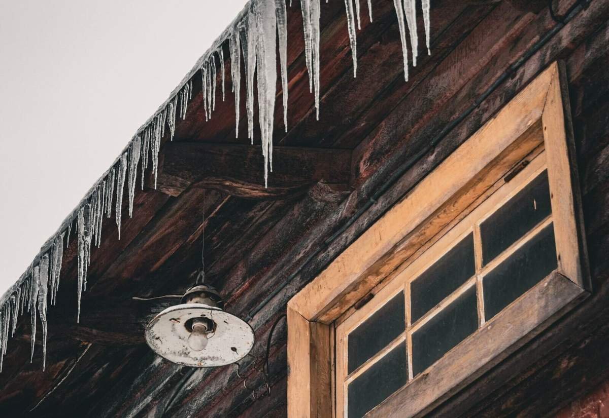 Icicles hanging from a roof eave, a sign of ice dam formation on Grand Rapids homes in winter