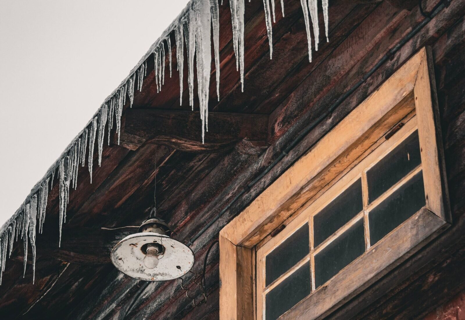 Icicles hanging from a roof eave, a sign of ice dam formation that makes rooftop DIY removal risky on Grand Rapids homes