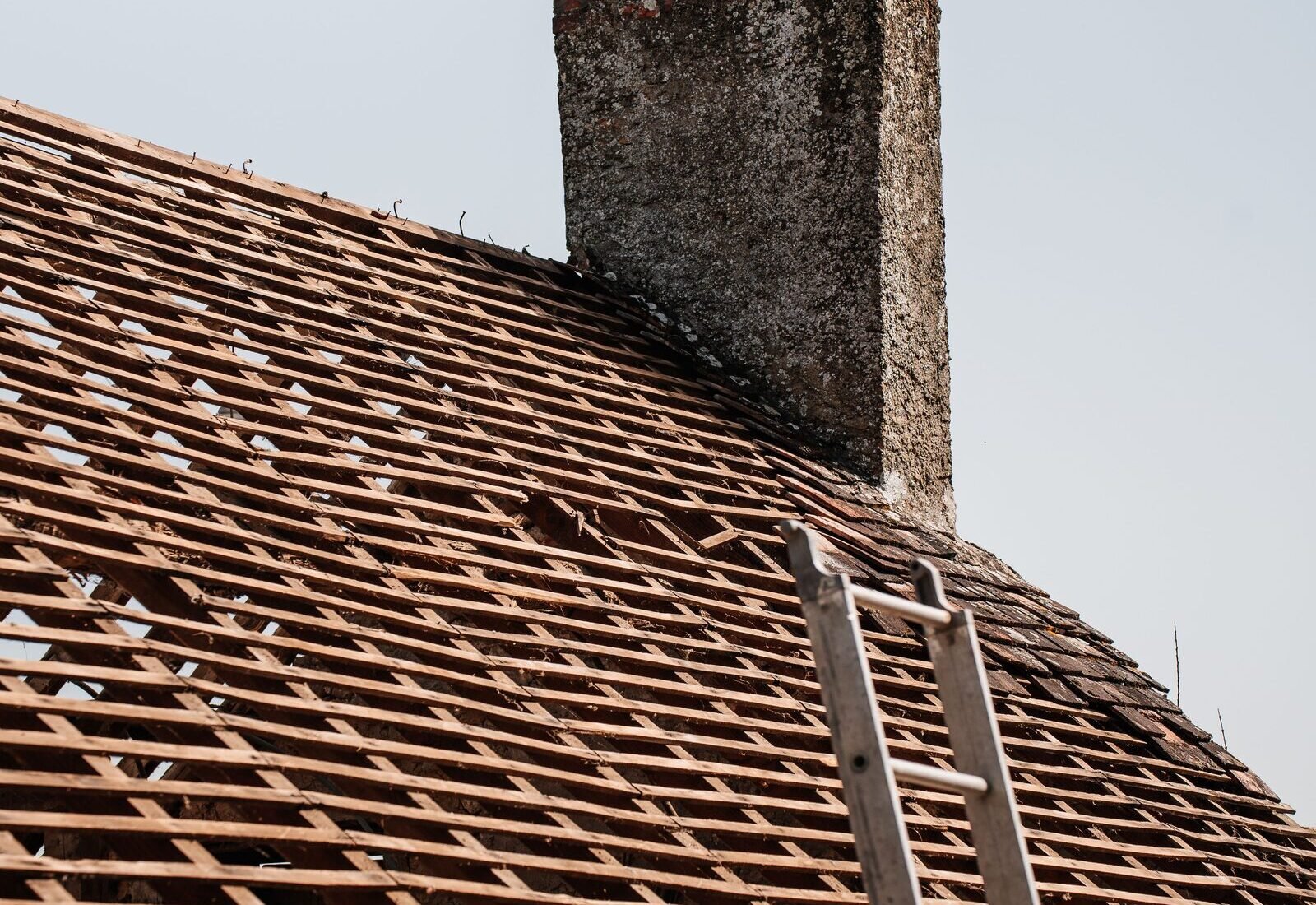 Roofing contractor on a ladder working near the chimney during a Grand&nbsp;Rapids roof job